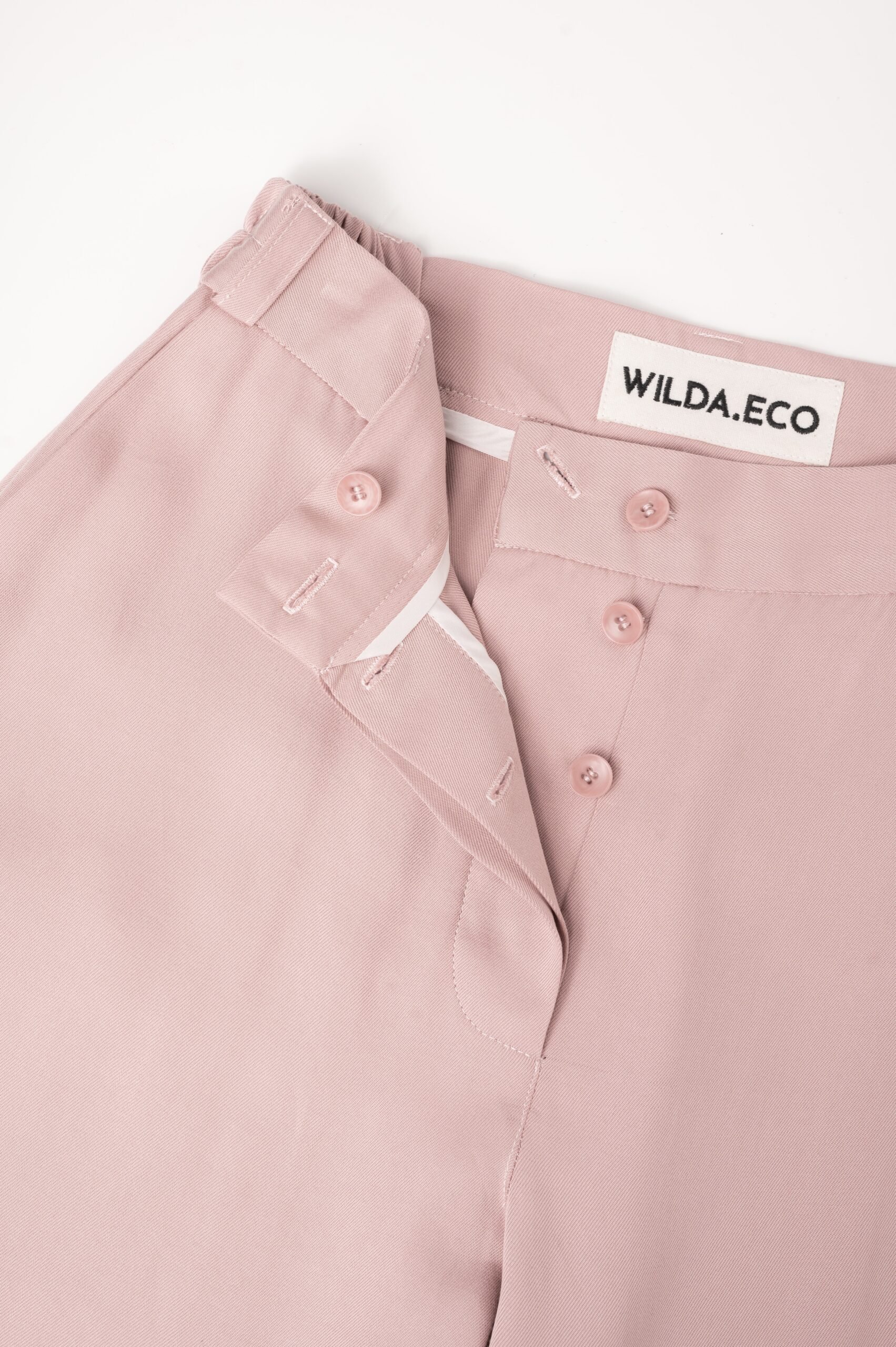 WILDA.ECO handcrafted rose pink trousers showcasing embroidered brand logo label